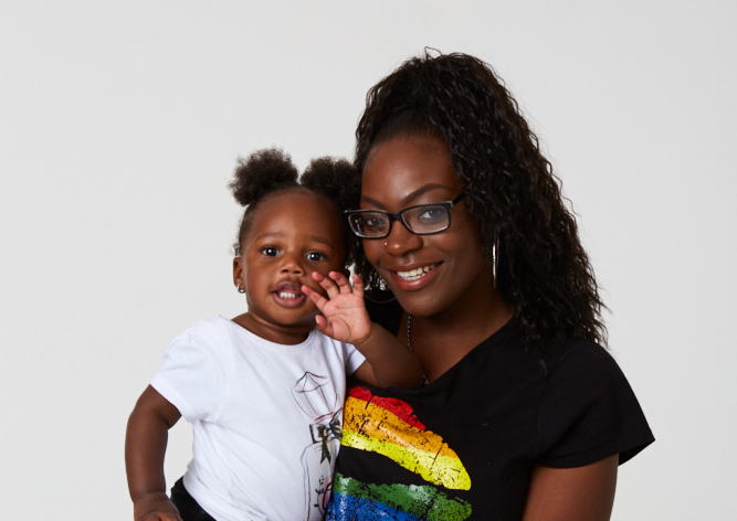 A woman in a rainbow shirt gently cradles a baby in her arms, radiating love and joy.