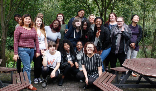 A group of about 10 young women stood together smiling for a group photo. They are outdoors.