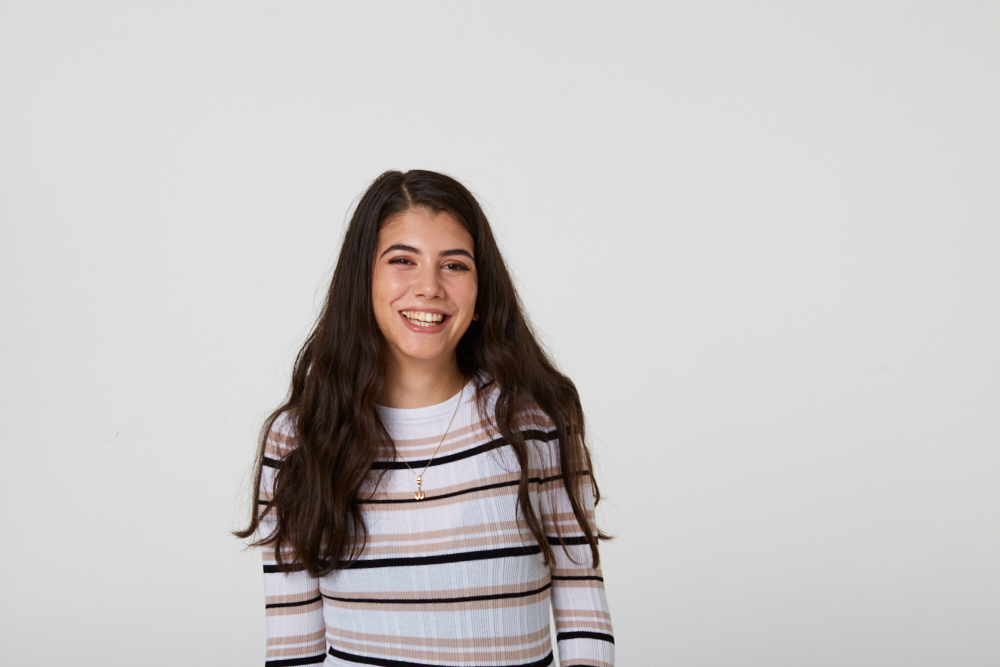 A young woman with long brown hair wearing a striped T-shirt smiling.