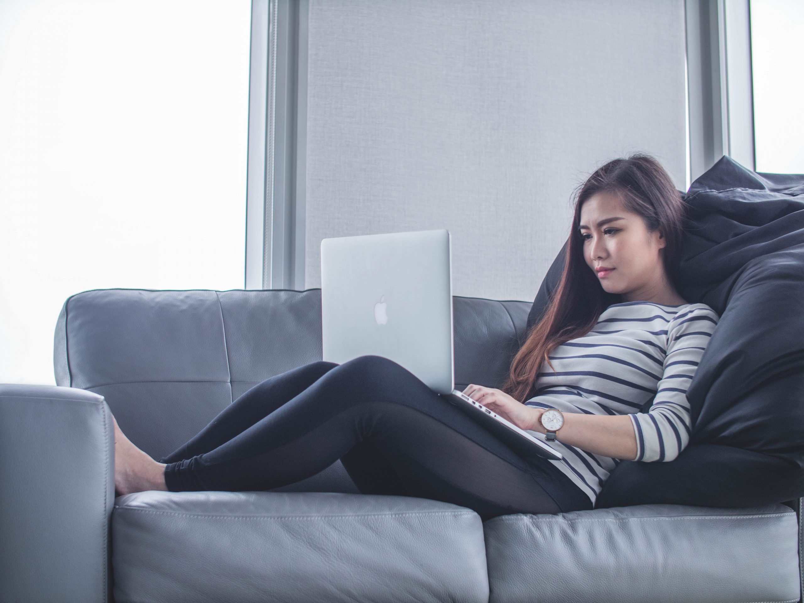 A young woman sat on a sofa on her laptop.