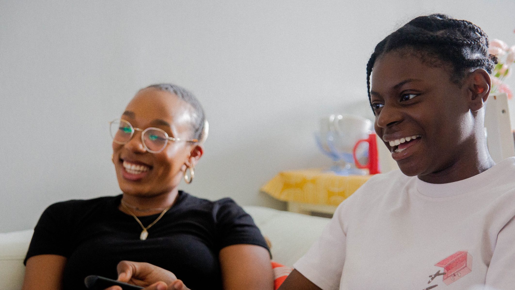 Two young women sitting side by side laughing