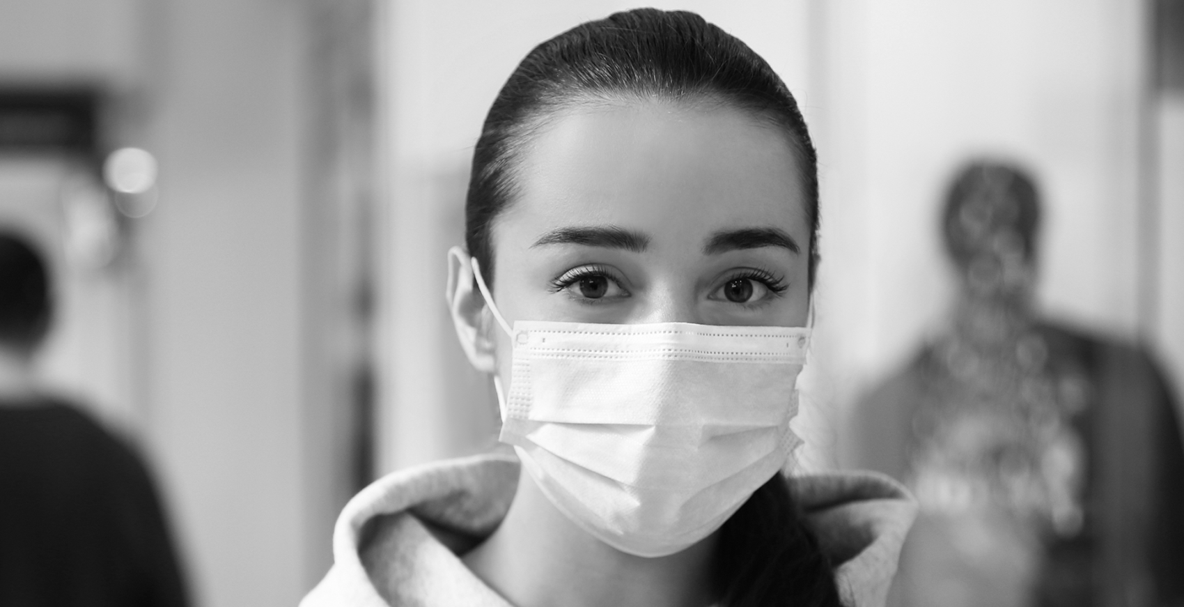 A women wearing a face mask looks into the camera