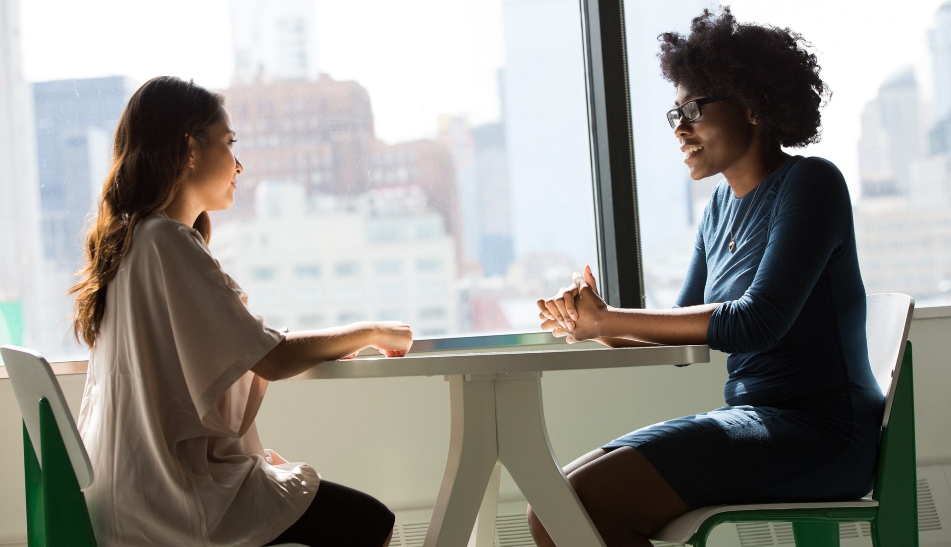 Two women talking sitting opposite each other at a table