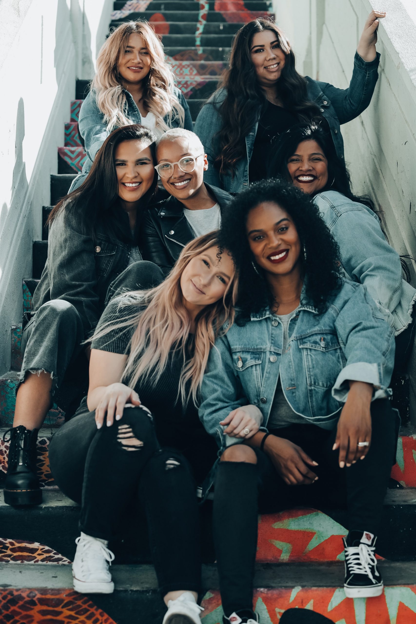 A group of young women sat on stairs smiling.