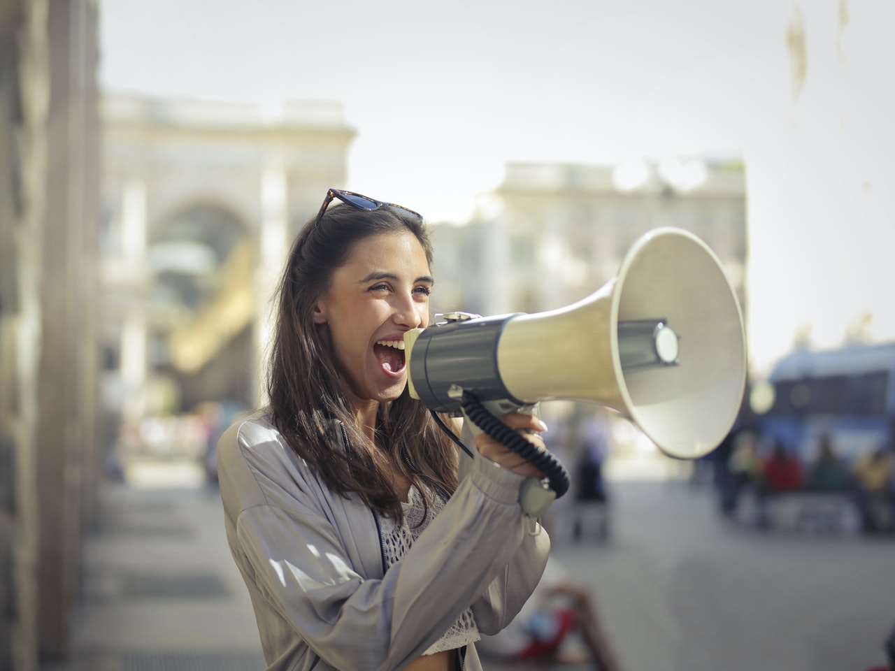 A young woman shouts into a large megaphone.