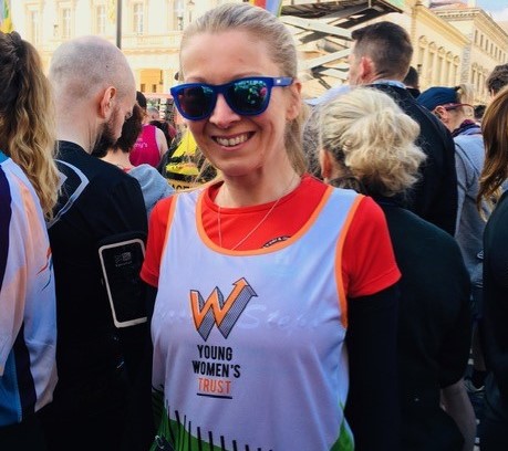 A woman wearing her running kit smiles at the camera