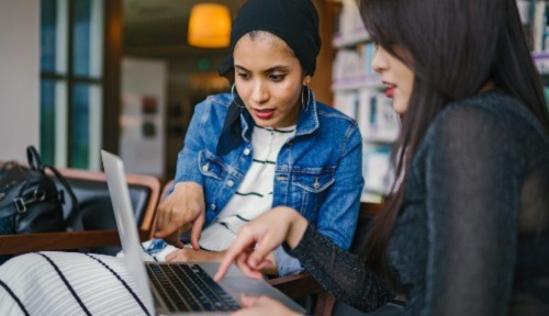 A young woman getting help from a coachon her laptop