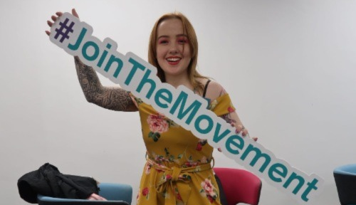 Young woman holding up a 'Join the movement' banner