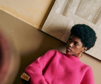 A young women in a bright pink jumper models Sezane's solidarity collection