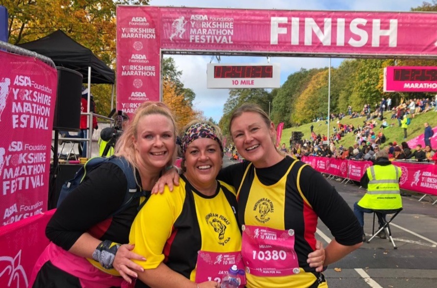3 female marathon runners hugging at the Yorkshire Marathon finish