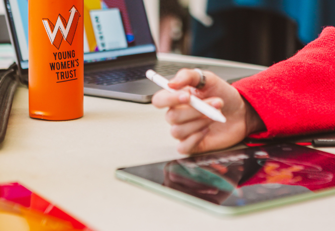 young woman's hand holding a pen, with a YWT branded bottle
