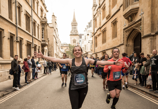several runners taking part in the Oxford Half Marathon, running past an Oxford landmark
