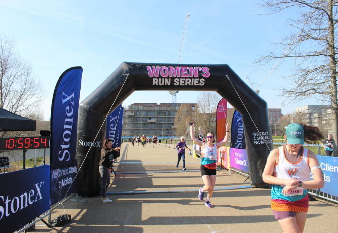 several women running under an inflatable arch which reads 'Women's Run Series'
