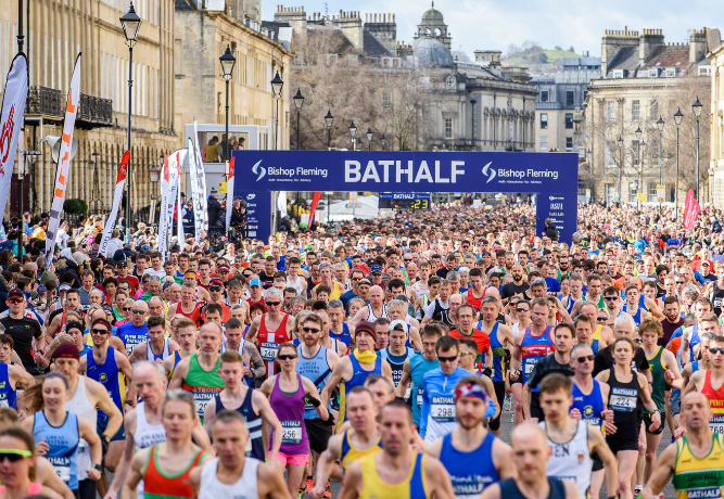 a huge crowd of people running through Bath for the Bath Half Marathon