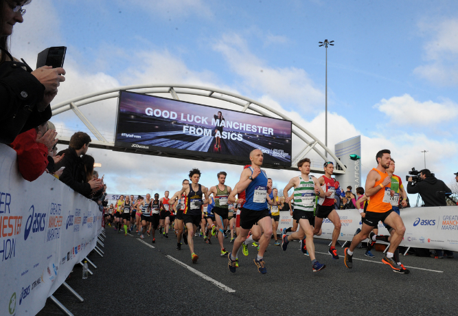 Group of runners passing under a good luck banner at the Manchester Marathon