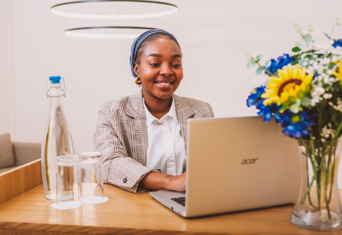a woman looking at the screen of her laptop, smiling
