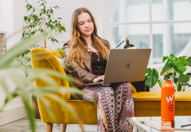 a young woman looks at her computer screen, reading something