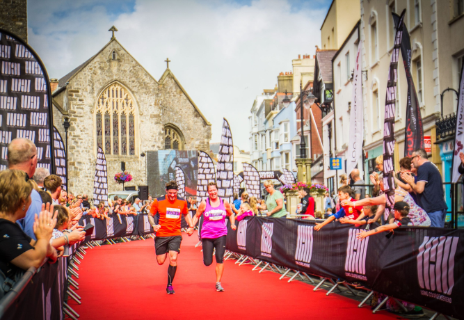 people taking part in a run in Wales, with people cheering along the streets